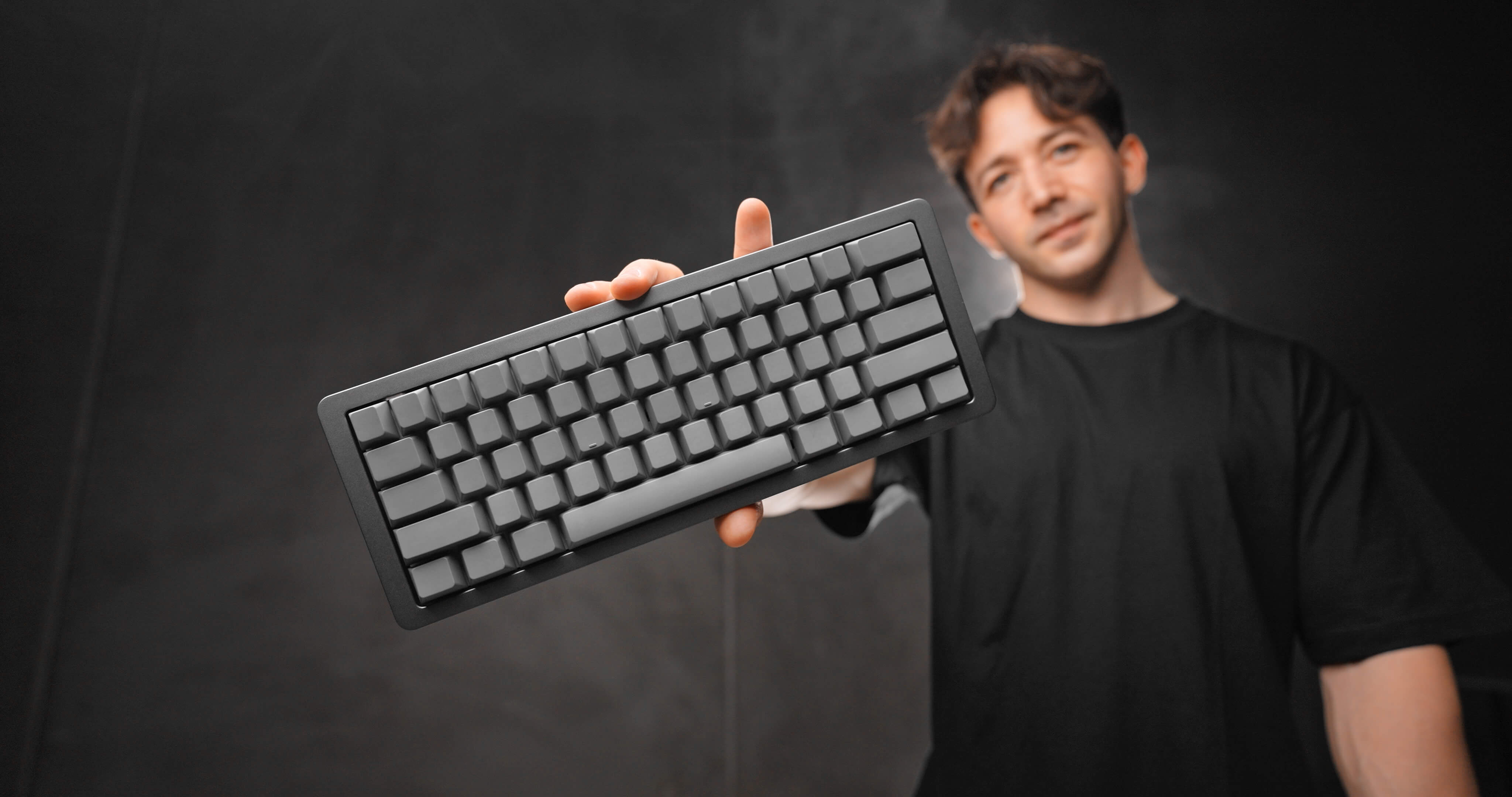 Optimum tech holding a Wooting 60HE with an Optimum case and keycap set.